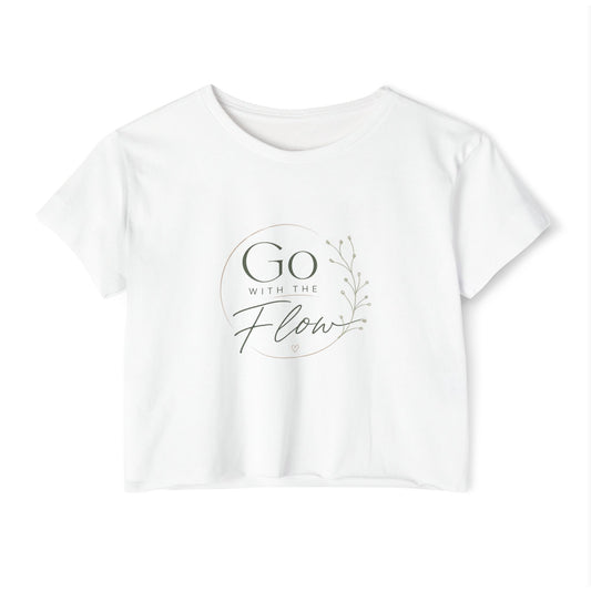 A white short-sleeve crop top t-shirt with a circular graphic on the chest that reads 'Go with the Flow' in a dark gray font, accompanied by a delicate leafy branch illustration. Clothing and apparel for body contouring specialists, massage therapists and beauty professionals.
