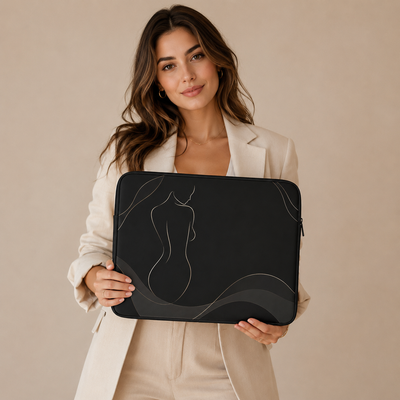 A woman in a beige blazer holds a black laptop sleeve featuring a minimalist white line art design of a female silhouette. Laptop cases, notebooks, clothing, and apparel for body contouring specialists and beauty professionals.
