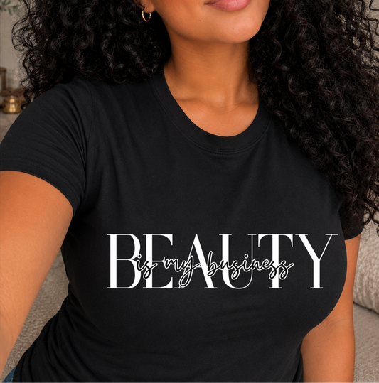 A woman wearing a black short-sleeve t-shirt with the text 'BEAUTY is my business' printed in white across the chest, shown in a close-up lifestyle shot. Shirts for beauty professionals and body contouring specialists.