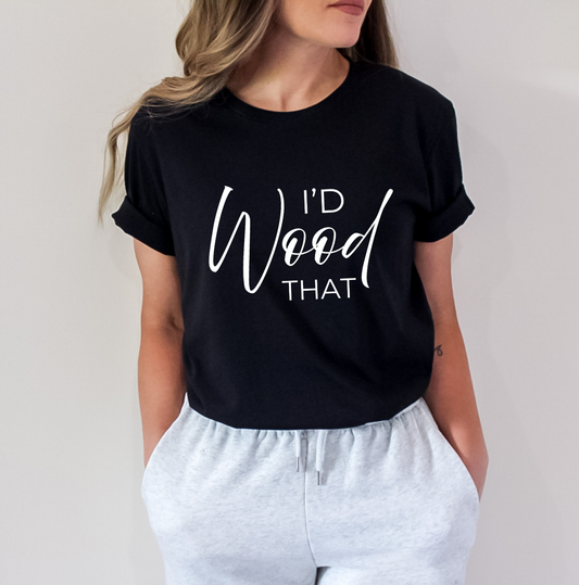A woman wearing a black short-sleeve t-shirt with white text that reads 'I'D Wood THAT' and light gray sweatpants, shown against a plain light gray background. Clothing and apparel for body contouring specialists and beauty professionals.