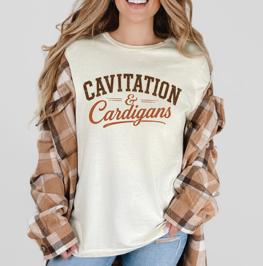 A woman wearing a cream-colored graphic t-shirt with 'CAVITATION & Cardigans' printed in brown and rust lettering, layered with an oversized brown and tan plaid flannel shirt. The background is a solid light gray. Clothing apparel, and accessories for body contouring specialists and beauty industry professionals.