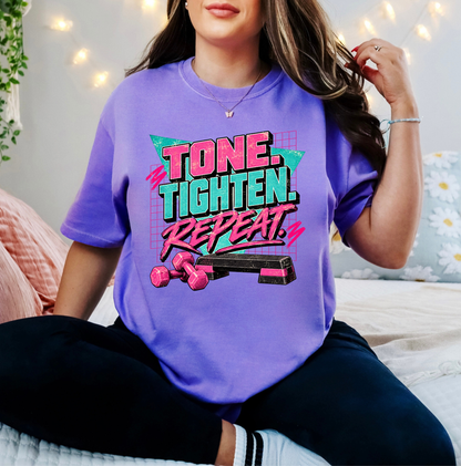 A woman wearing a purple graphic t-shirt with the text 'TONE. TIGHTEN. REPEAT.' Clothing, apparel, and accessories for body contouring specialists and beauty professionals.