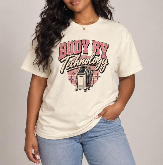 A woman wearing a cream-colored graphic t-shirt with pink and black lettering that reads 'BODY BY Technology' and a laser treatment illustration, paired with light blue jeans, against a neutral gray background. Clothing, apparel and accessories for body contouring specialists and beauty professionals.