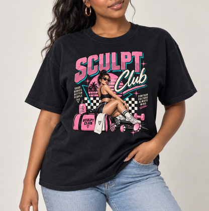 A woman wearing a black graphic t-shirt with a retro pink and teal 'SCULPT Club' design, paired with light wash blue jeans, photographed against a neutral light gray background. Clothing, apparel and accessories for body contouring specialists and beauty professionals.