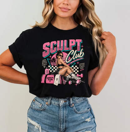 A woman wearing a black graphic t-shirt with a pink and white 'SCULPT Club' design, paired with distressed blue jeans, against a plain light gray background. Clothing, apparel and accessories for body contouring specialists and beauty professionals.